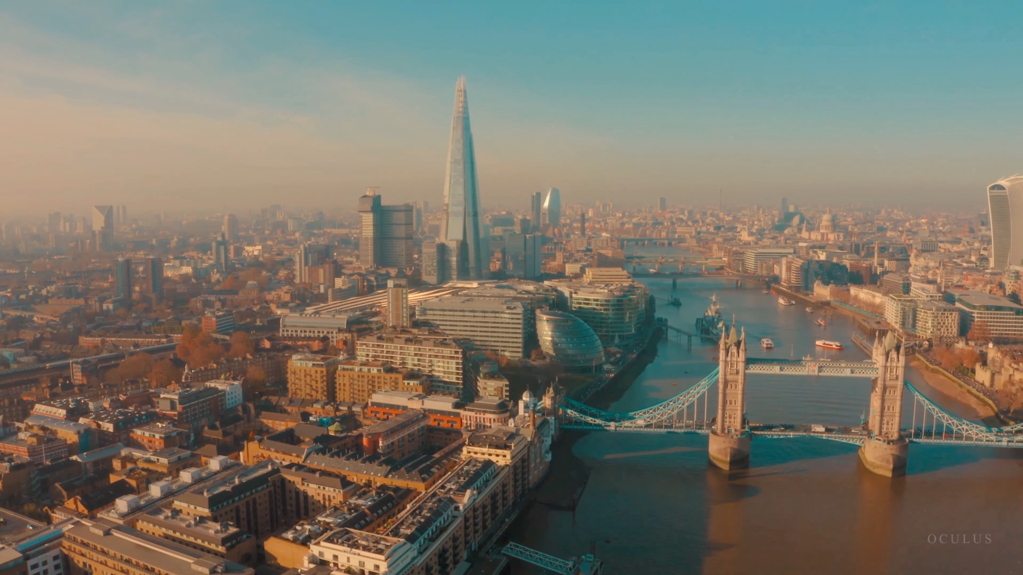 Aerial view of the London skyline at dusk, looking over Tower Bridge and the Shard